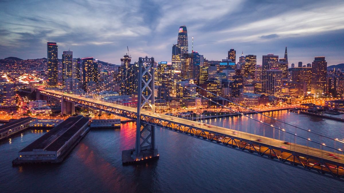 Illuminated bridge by a glowing city skyline under a twilight sky near Warwick San Francisco