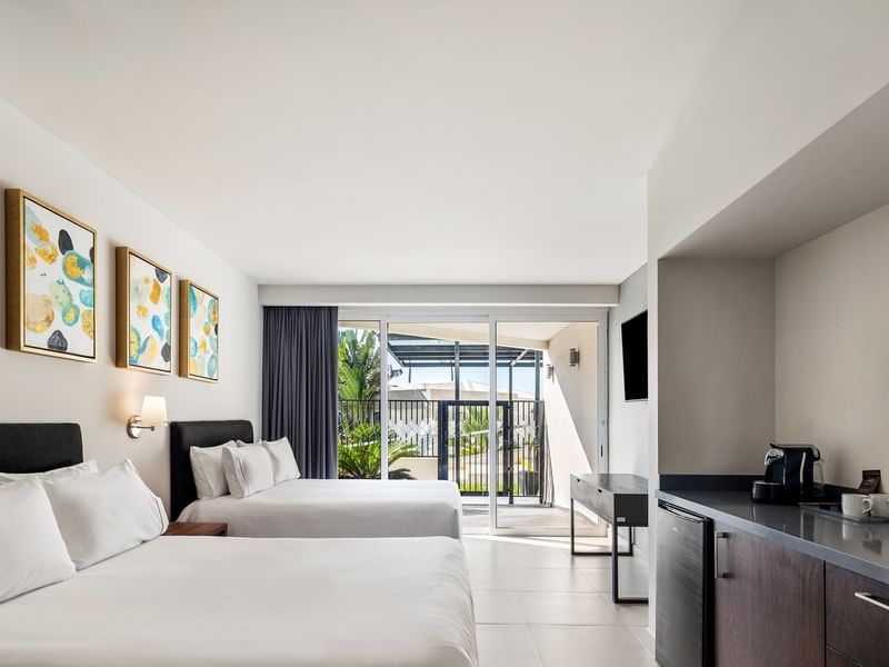 Villa Cora, featuring two beds, colorful wall arts, a small kitchenette, and a coffemaker at Sunvivia Mazatlán