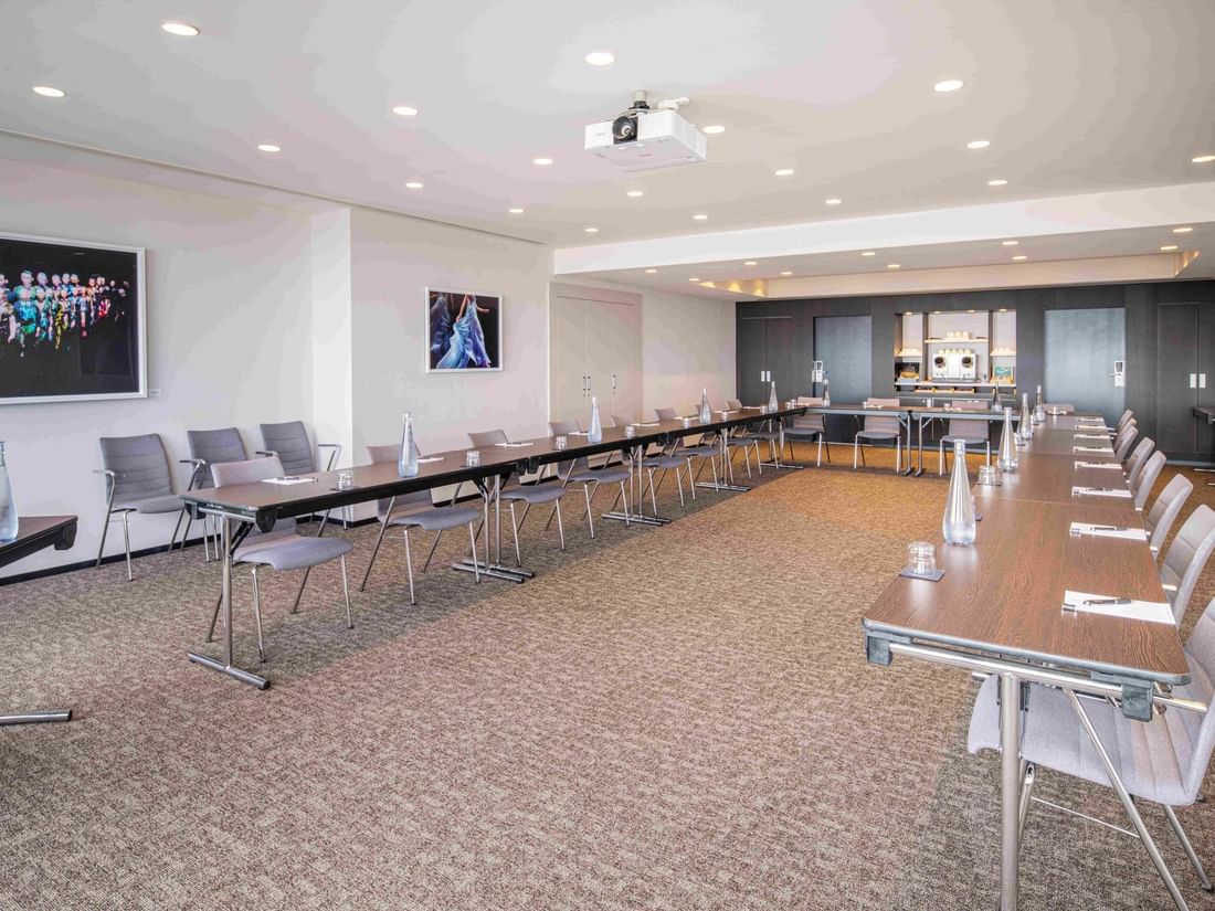 Meet 26 One conference room with a long table, chairs, artwork on walls, and a projector at The Hotel Brussels