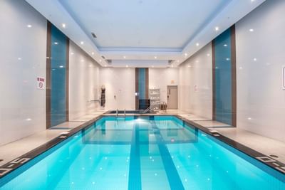 Indoor pool with adjacent hot tub, metal handrails and tiled floor at Winnipeg Airport Hotels