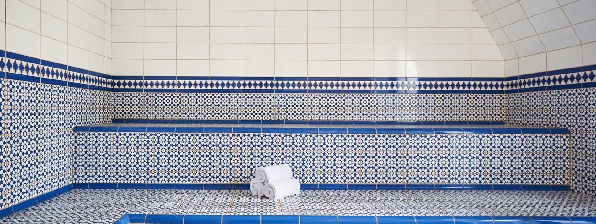 Relaxing steam room at Hotel Westminster Paris, featuring white and blue tiled walls, with towels placed on the benches