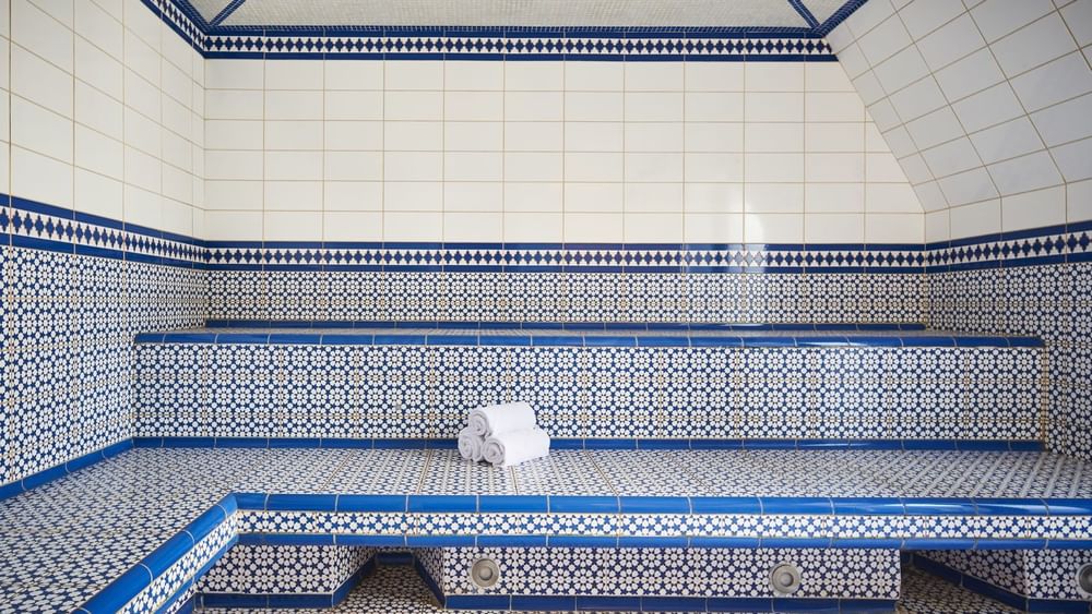 Relaxing steam room at Hotel Westminster Paris, featuring white and blue tiled walls, with towels placed on the benches