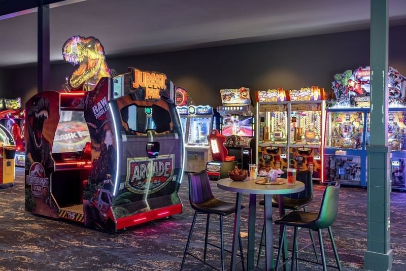 Modern arcade room with a Jurassic Park game, claw machines, and a high table at Shangri-La Resort and Golf Club