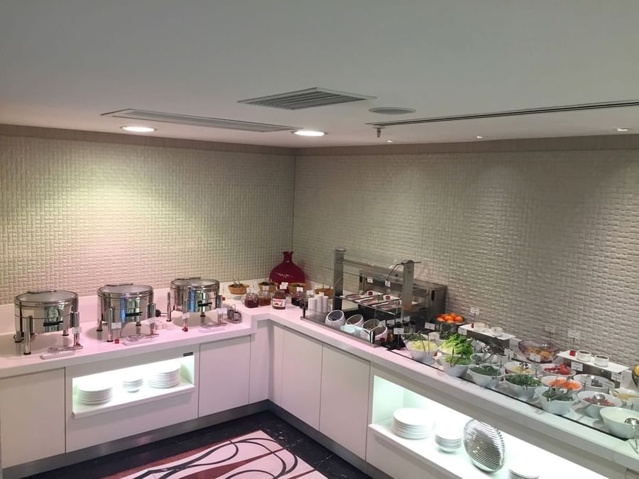 Breakfast buffet by a white counter surrounding fresh fruit and salad bowls in Breakfast & In-Room Dining at Warwick Ankara