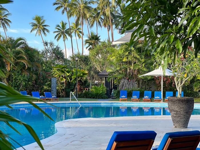 A pool surrounded by blue lounge chairs and lush greenery at Naviti Resort Fiji Coral Coast.