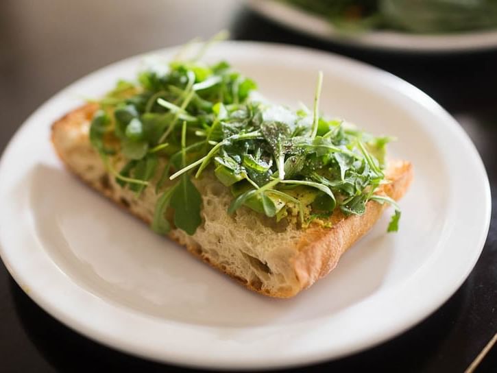 Plate of toasted bread topped with greens at Pickwick San Francisco.