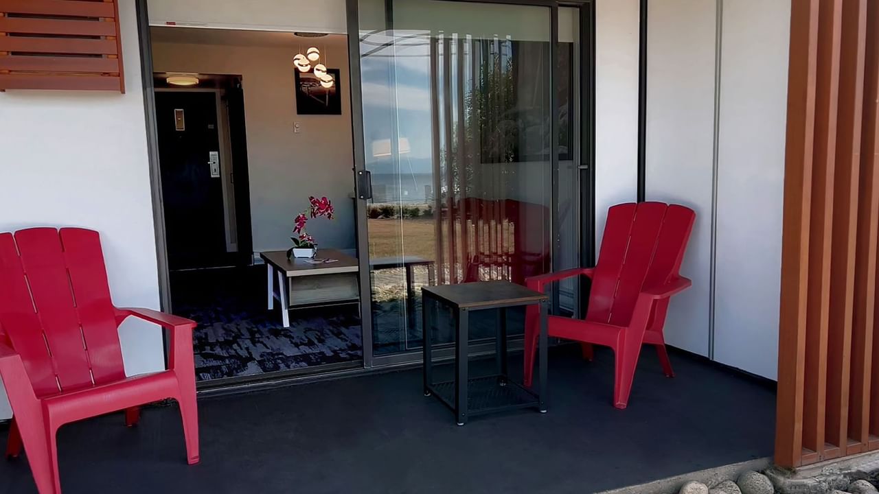Patio area of guest room with sliding doors and red deck chairs