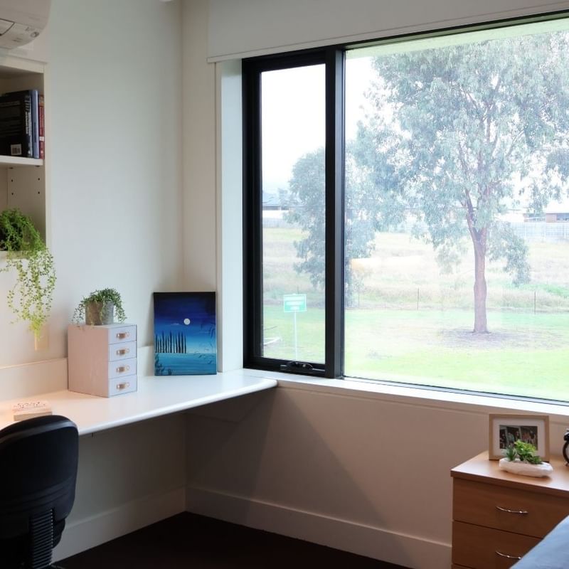 Cozy room with desk, books, and nature view at La Trobe University.