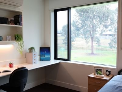 Cozy room with desk, books, and nature view at La Trobe University.