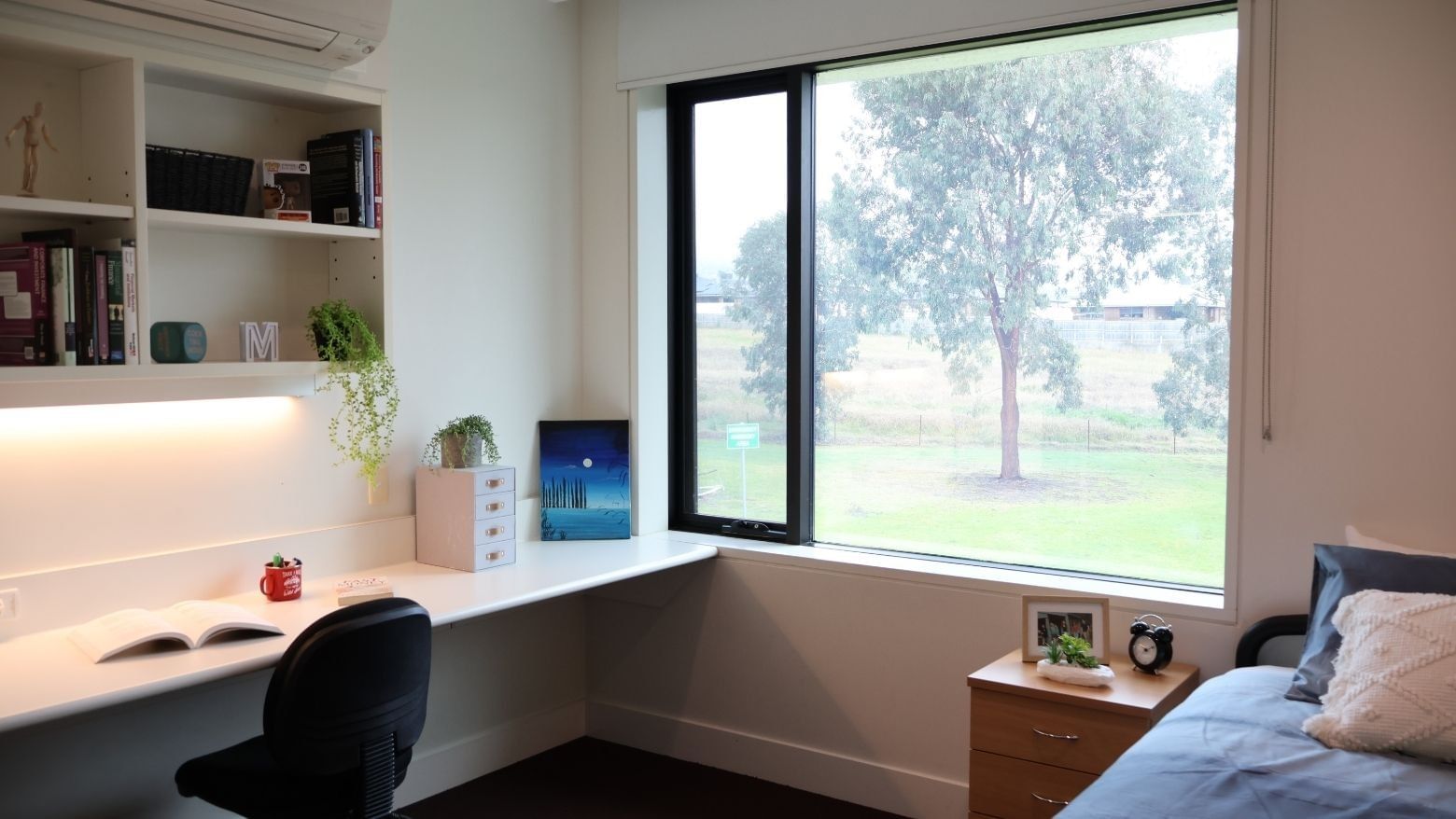 Cozy room with desk, books, and nature view at La Trobe University.