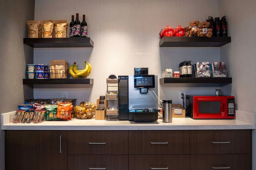 A display of a coffee maker, snacks, and various items arranged on shelves at Hotel 43