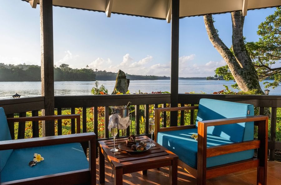 Blue chairs and table with refreshments on a deck overlooking water at Warwick Le Lagon - Vanuatu.