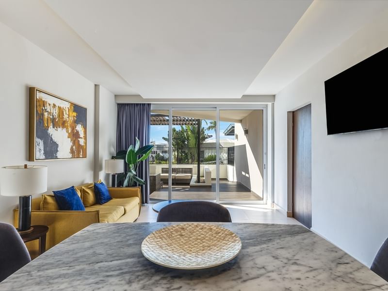 Villa Cora living room with a yellow sofa, marble table, and large balcony doors at Sunvivia Mazatlán