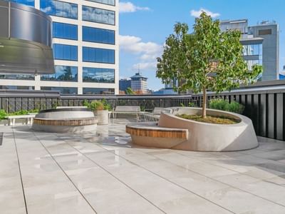 Modern rooftop terrace with curved planters, wooden benches, and city skyline views at UniLodge Auckland Central.