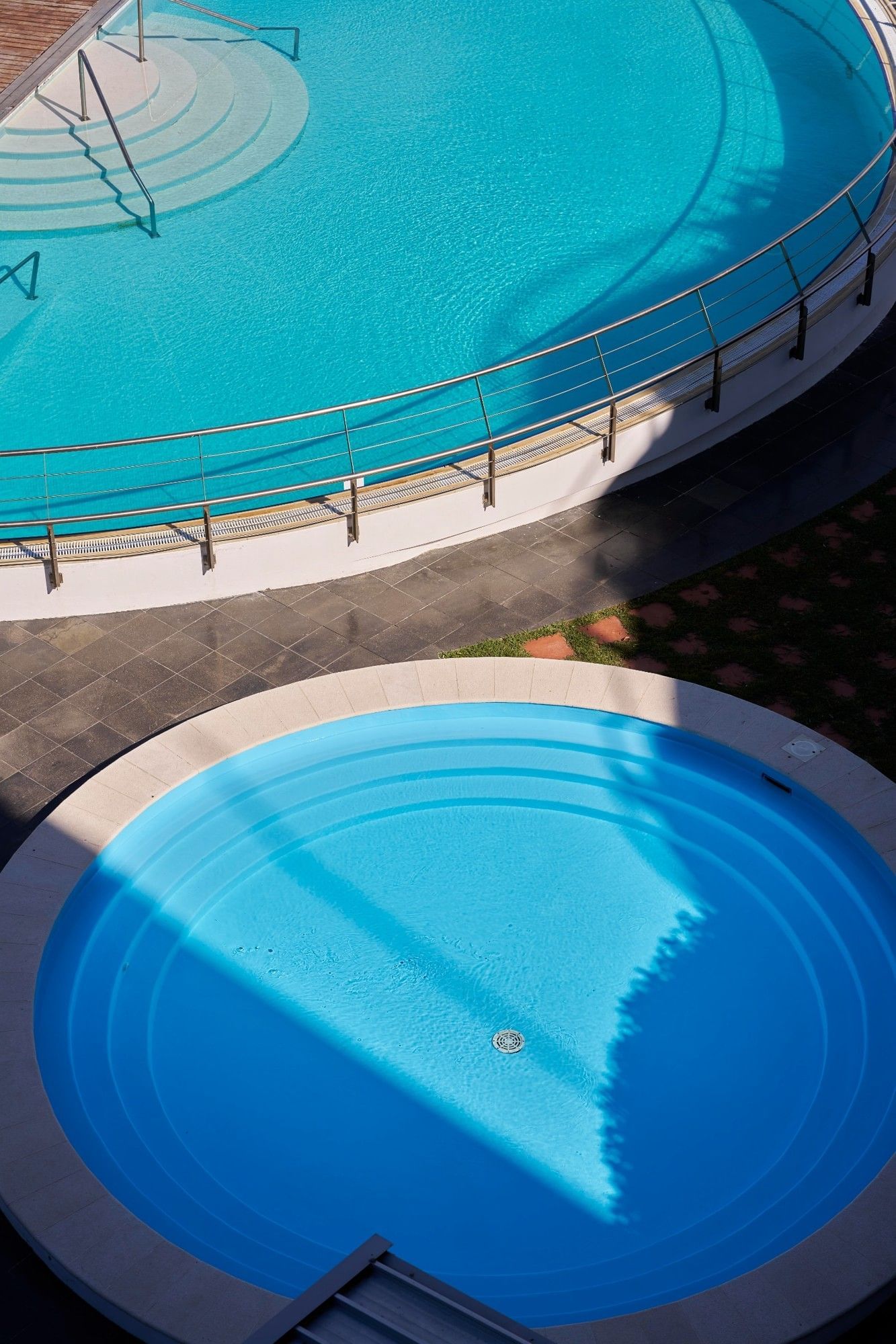 Overhead view of the swimming pools at Hotel Do Caracol with clear blue water under the sun