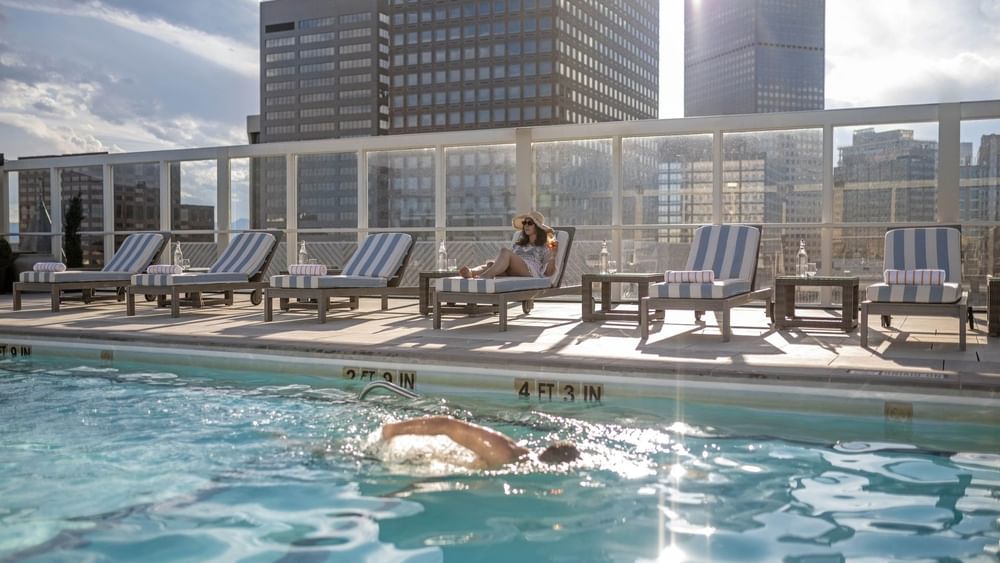 Guest swimming in the rooftop pool near loungers under the bright sun at Warwick Denver