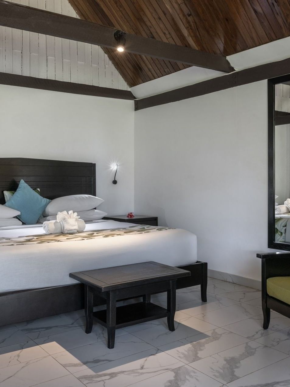 Modern bed with a black headboard and a dark armchair in Garden View Villa at Tambua Sands Beach Resort