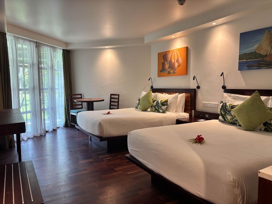 Two beds with tropical decor and wooden floors in a spacious room at Warwick Fiji Resort and Spa.