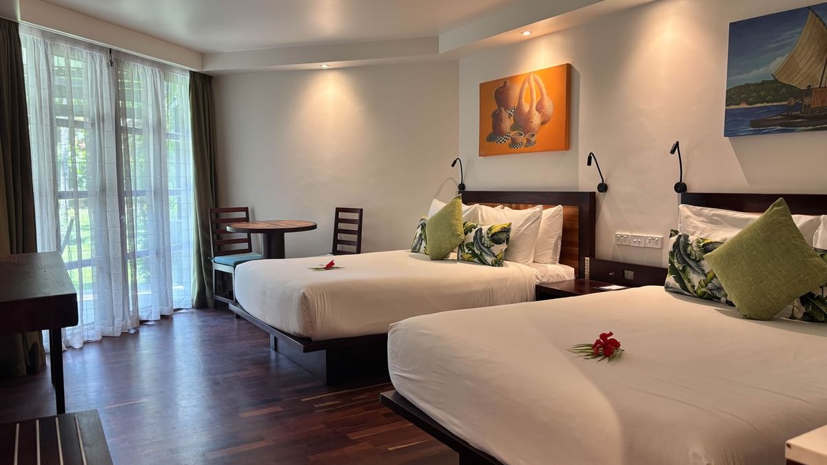 Two Garden View Two Double Rooms with wooden floors and white linens at Warwick Fiji in Korolevu.