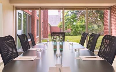 Modern boardroom table with black mesh chairs facing large windows at Spencer Hotel, ideal meeting rooms London Ontario