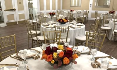 Round banquet tables with floral centerpieces and gold Chiavari chairs in the ballroom at Avon Old Farms Hotel