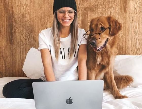 Lady posing with her dog on a bed at Aava Whistler Hotel