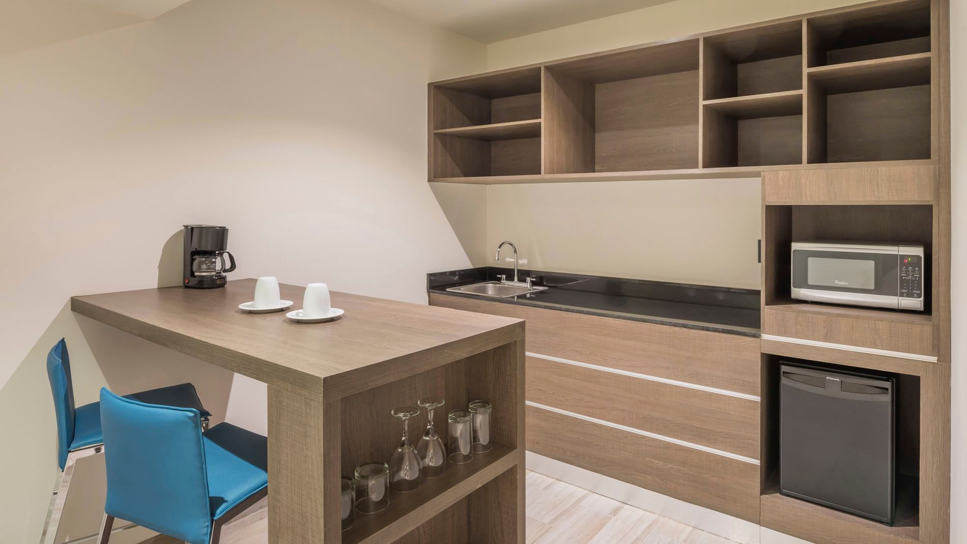 King Junior Suite in-room kitchenette with wood cabinetry, a microwave, and coffee maker setup at Real Inn Celaya