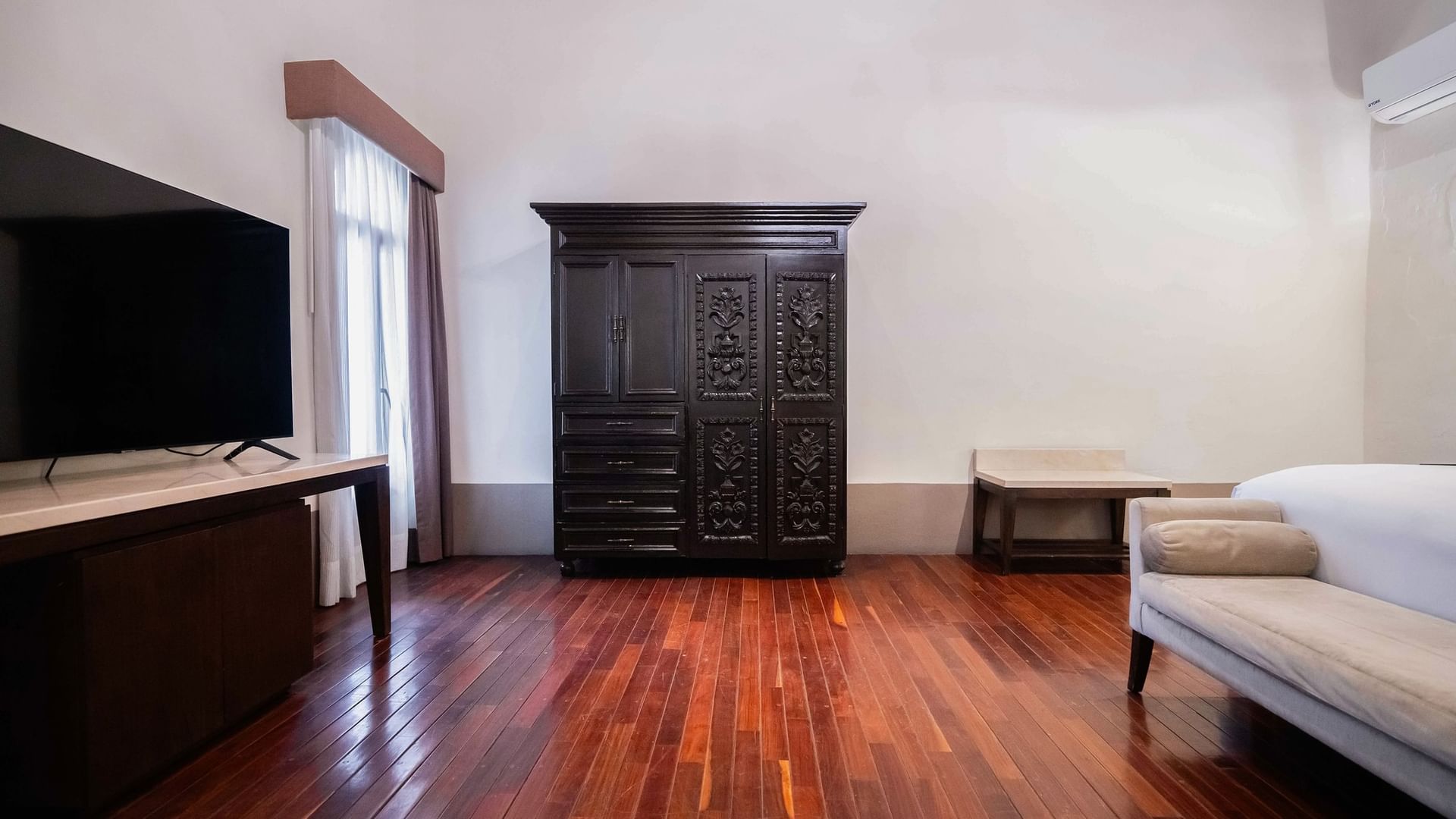 Elegant King Superior room with hardwood floors and a large carved wardrobe at Quinta Real Puebla