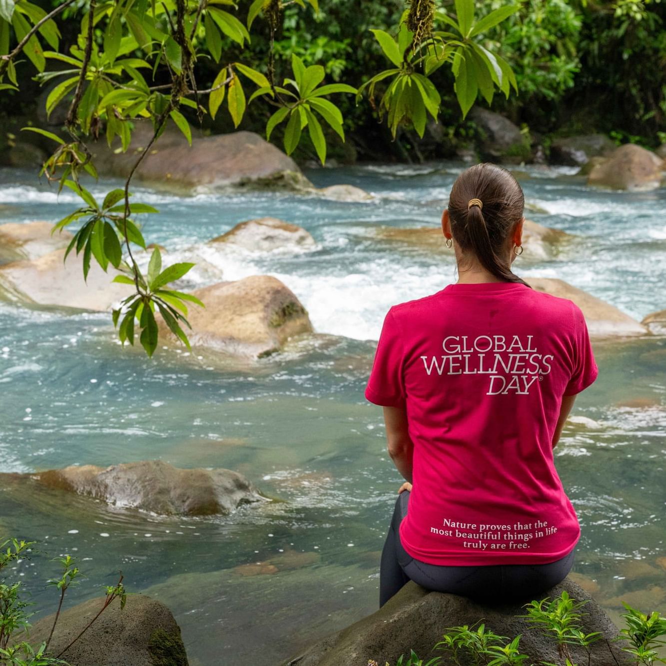 Woman sitting on a rock looking at the river near Hideaway Rio Celeste