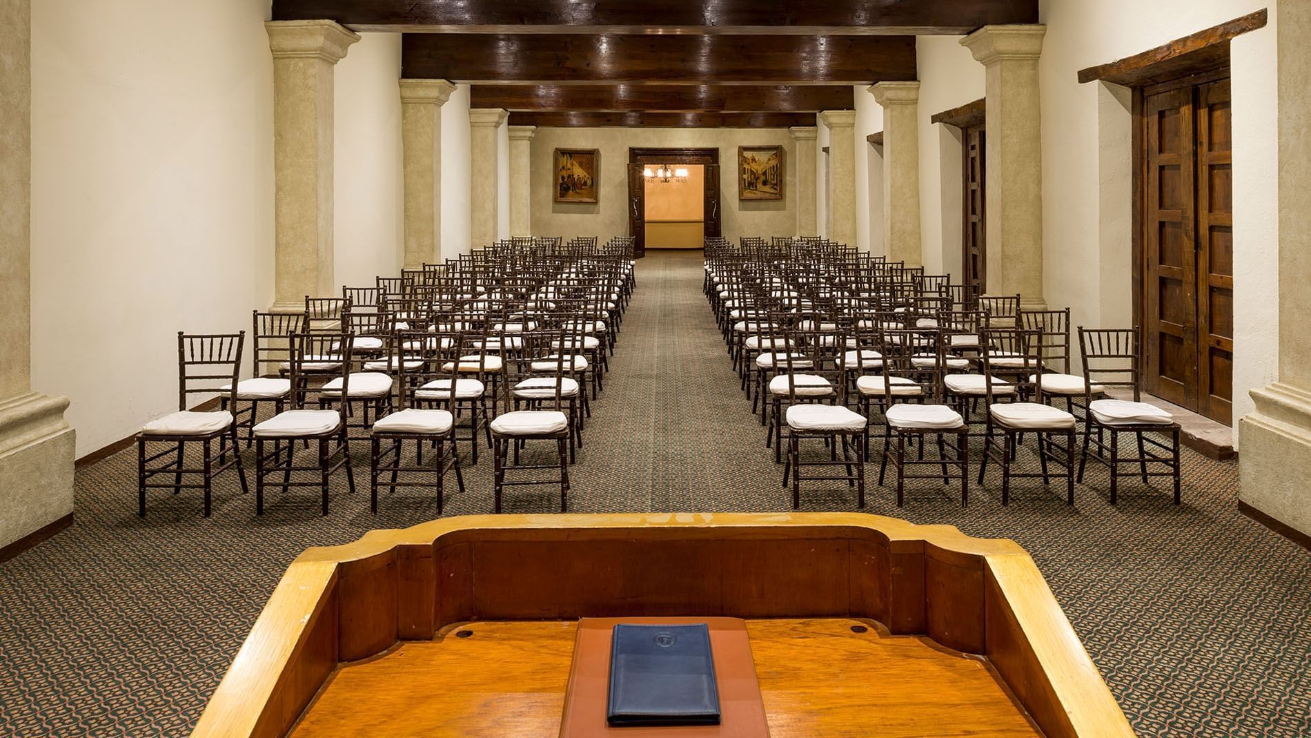 San Pedro meeting room with rows of chairs facing a wooden lectern under beamed ceilings at Quinta Real Zacatecas