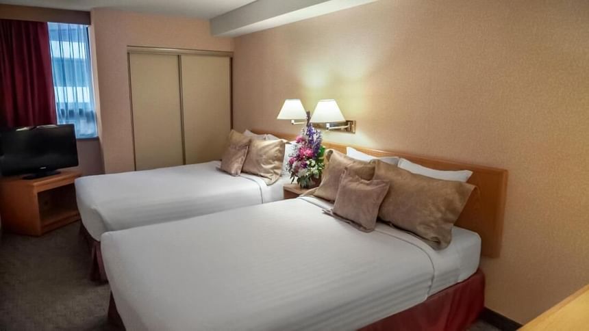 Deux lits confortables dans une chambre d'hôtel au Cartier Place Suite Hotel