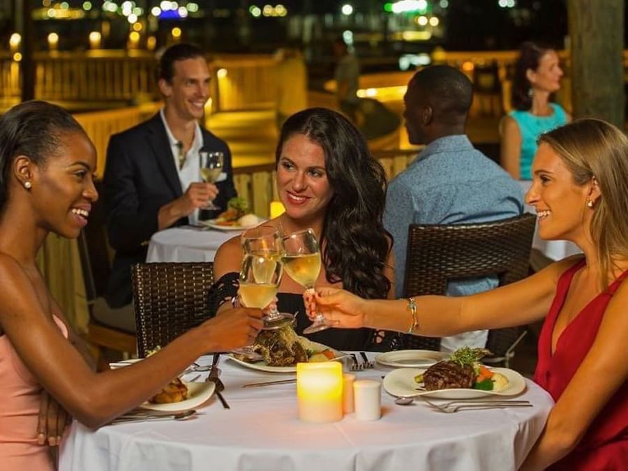 Guests toast wine by candlelit tables under a night sky surrounding a harbor at Warwick Paradise Island Bahamas