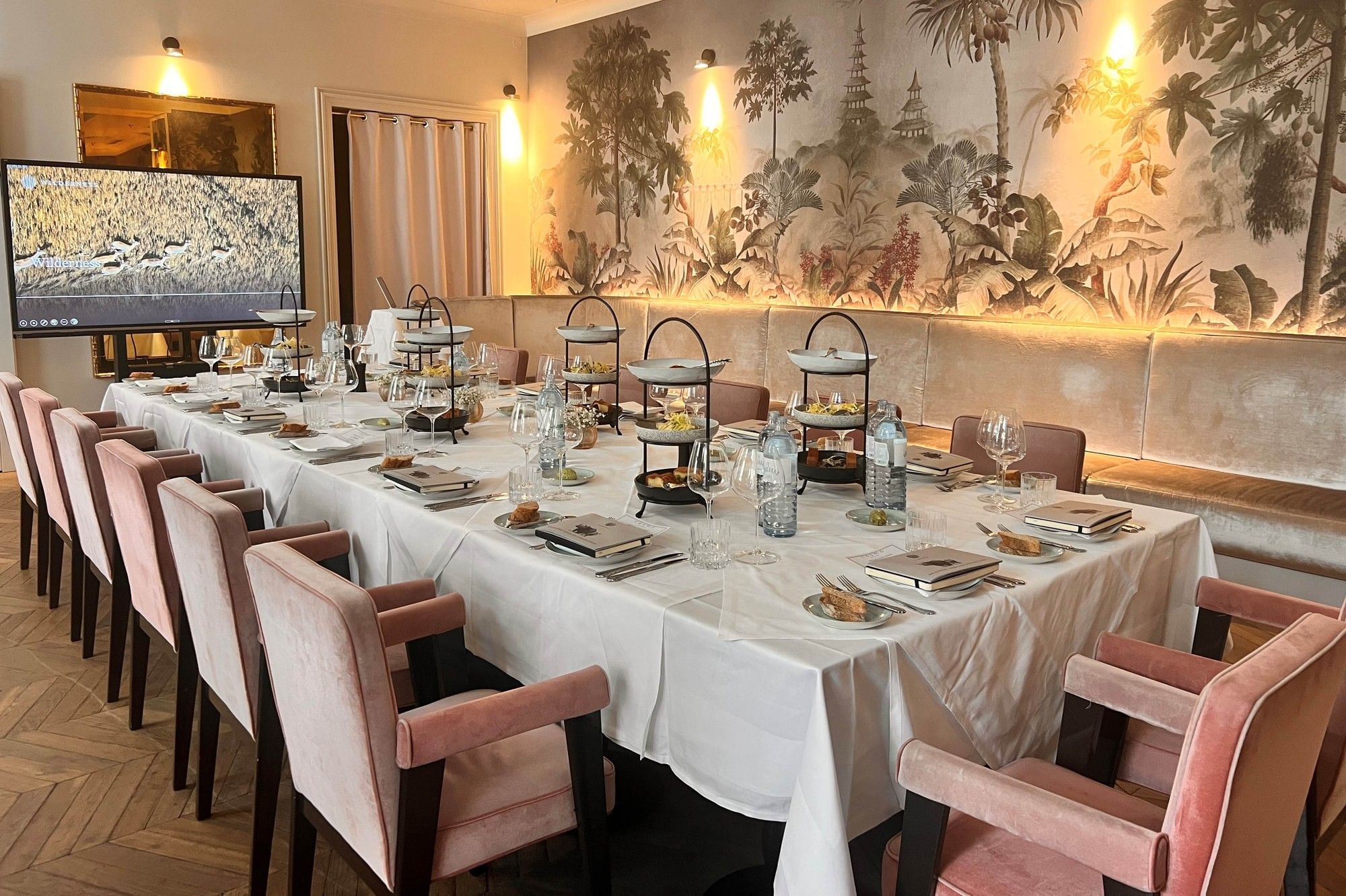 Private dinner setting in Salon Jungle at Hotel THE LEO GRAND with an elegantly set table, pink chairs and tropical wall art