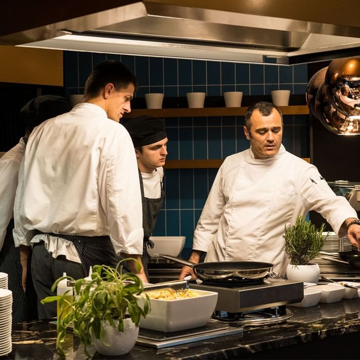 Head chef teaching Juniors in a kitchen at Falkensteiner Hotels