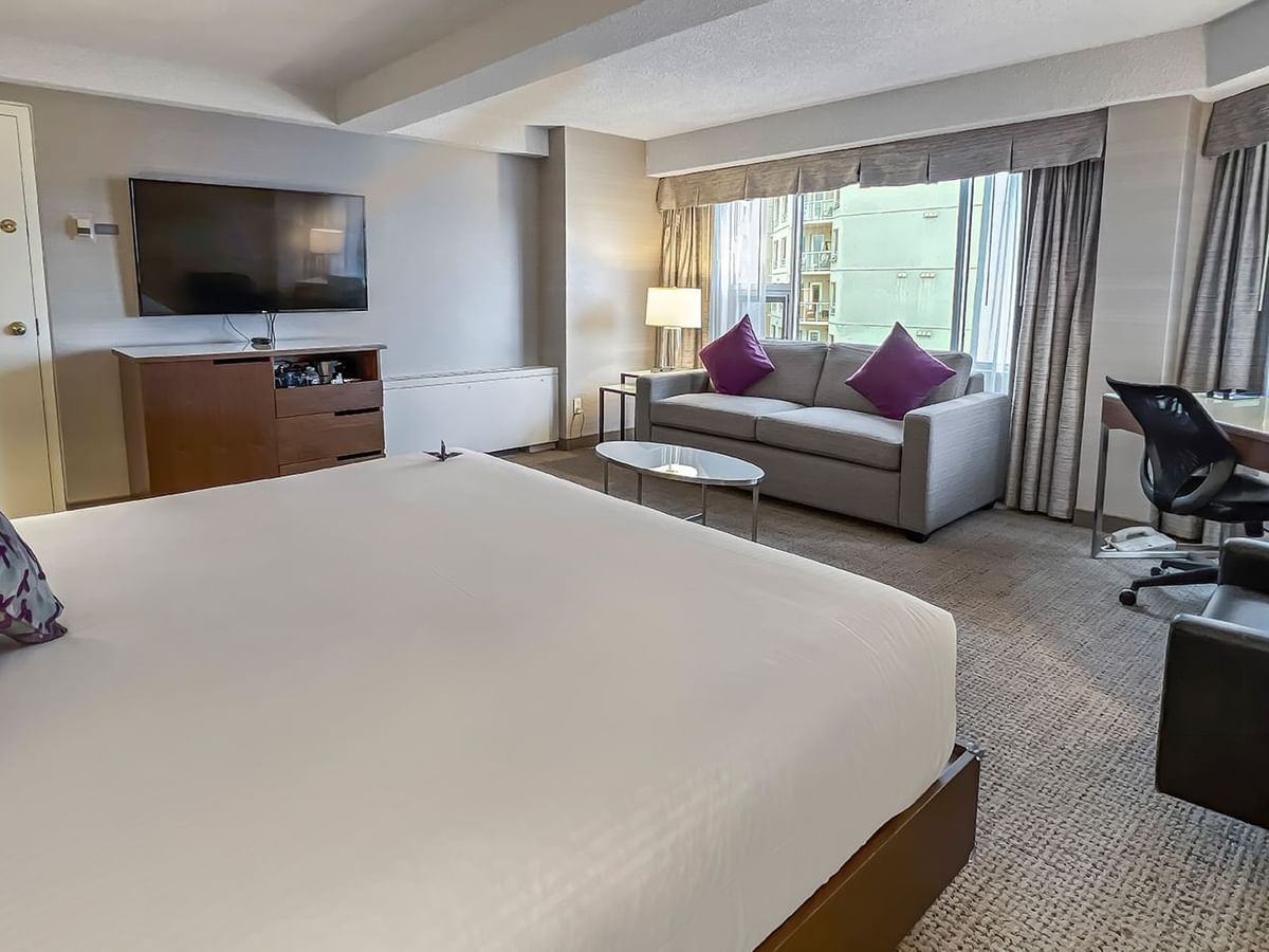 Hotel bedroom with bed, sofa bed, TV, and table