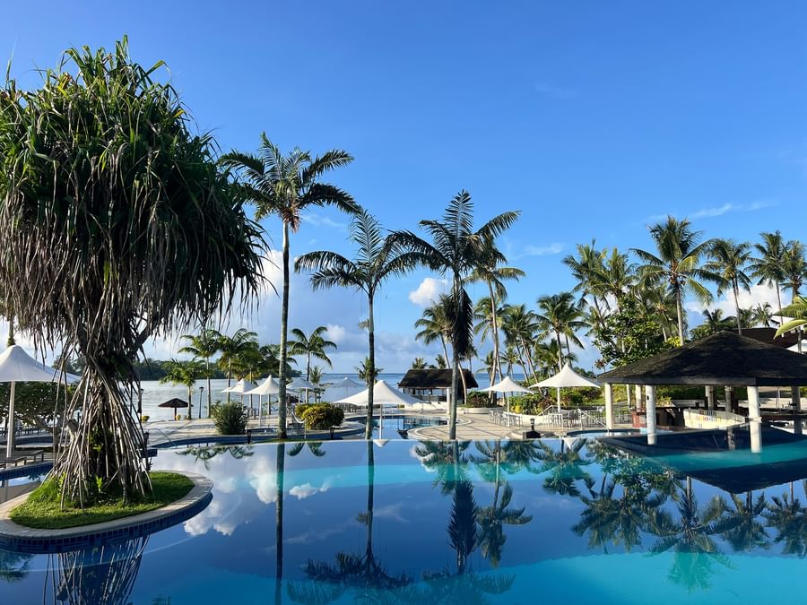 Tropical pool area with lush greenery and palm trees at Warwick Le Lagon - Vanuatu.