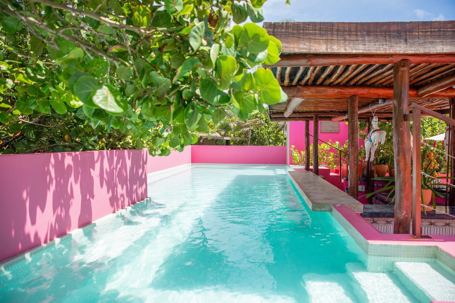 La Zebra's turquoise rooftop pool beside a pink wall and wooden swim-up bar