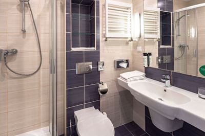 Bathroom with shower, sink, toilet, and towels in a room at Metropol Hotel