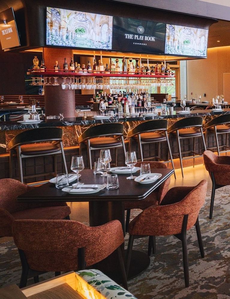 The Playbook Commons bar and restaurant with clean round dining tables and plush armchairs inside luxury Hotel X Toronto