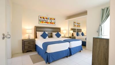 Twin beds with blue runners and pillows next to a large mirrored wardrobe in One Bedroom at Worthing Court Apartment
