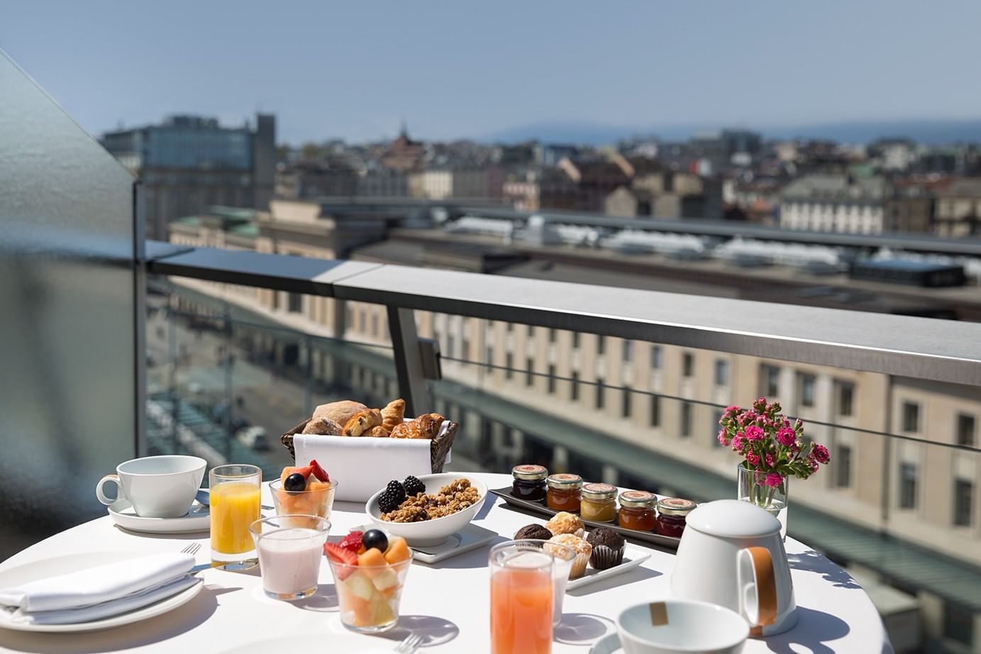 Fresh breakfast tray by a vase of pink flowers on a table in Penthouse Terrace Room at Warwick Geneva