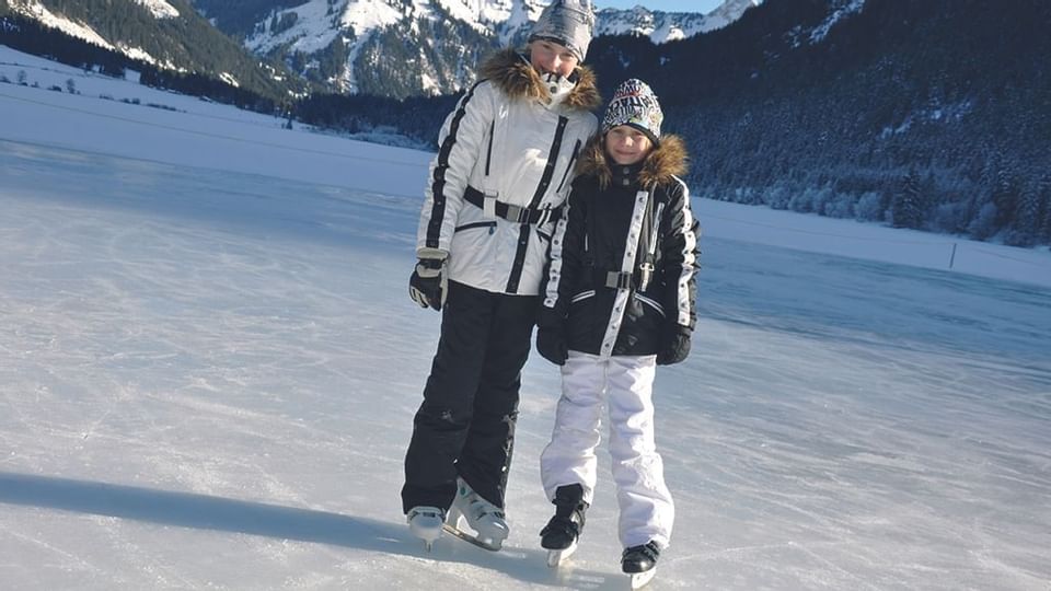 Two kids in skates posing at a snowy valley near Liebes Rot