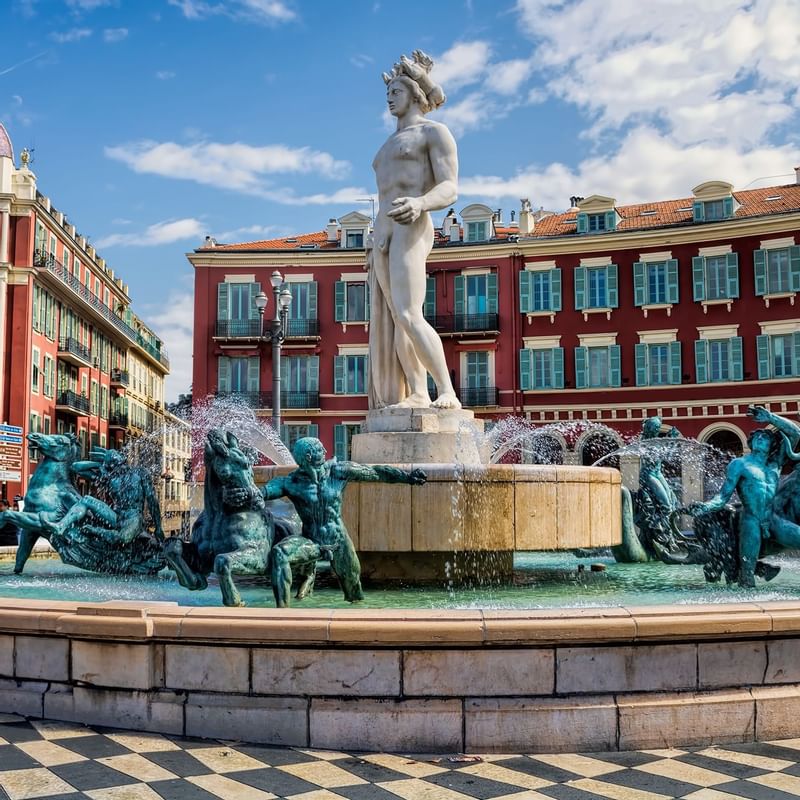 A scenic view of Nice square place, showcasing a prominent fountain surrounded by buildings near Warwick Hotels and Resorts