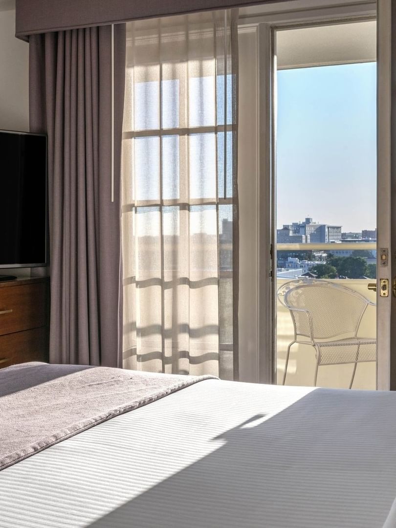 View of a bedroom with a TV by a window through white French doors in Executive Suites at Warwick Denver