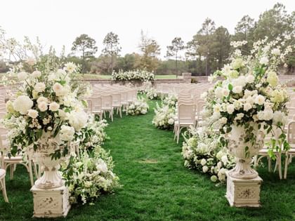 Chairs and floral arrangements on green lawn for a wedding at Camp Creek Inn Inlet Beach.