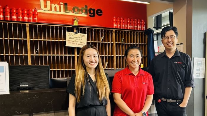 Three people smiling and posing for a photo in front of a reception desk.