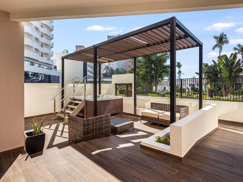 Villa Cora terrace featuring a wooden pergola, outdoor seating, and a hot tub on a sunny day at Sunvivia Mazatlán