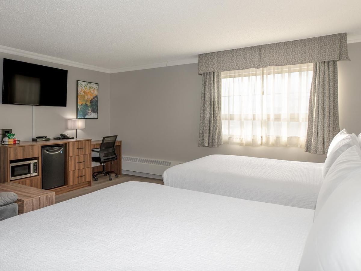 Two queen beds, desk, TV, and window.