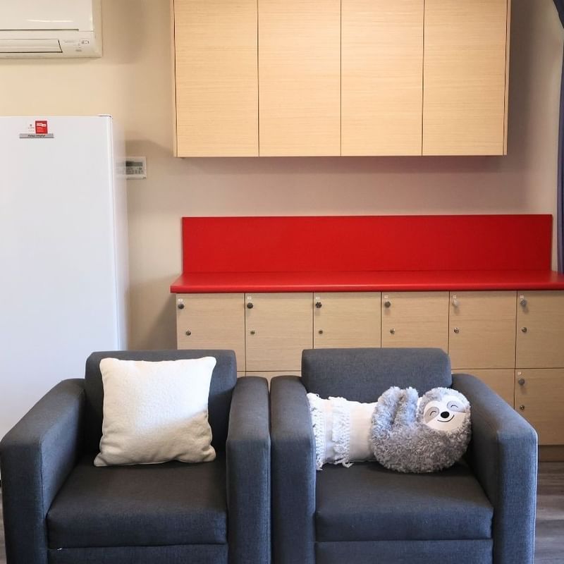 Two comfortable chairs with pillows and stuffed toy in a modern Hillside Apartments living space.