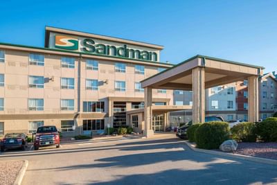 Front view of Sandman Hotel & Suites Winnipeg Airport with parked vehicles